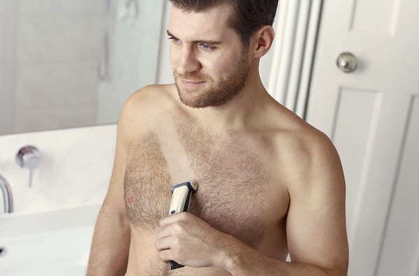 man trimming body hair with clipper